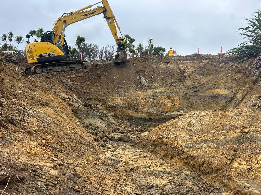 A large excavator moving dirt at the top the Ararua Road slip